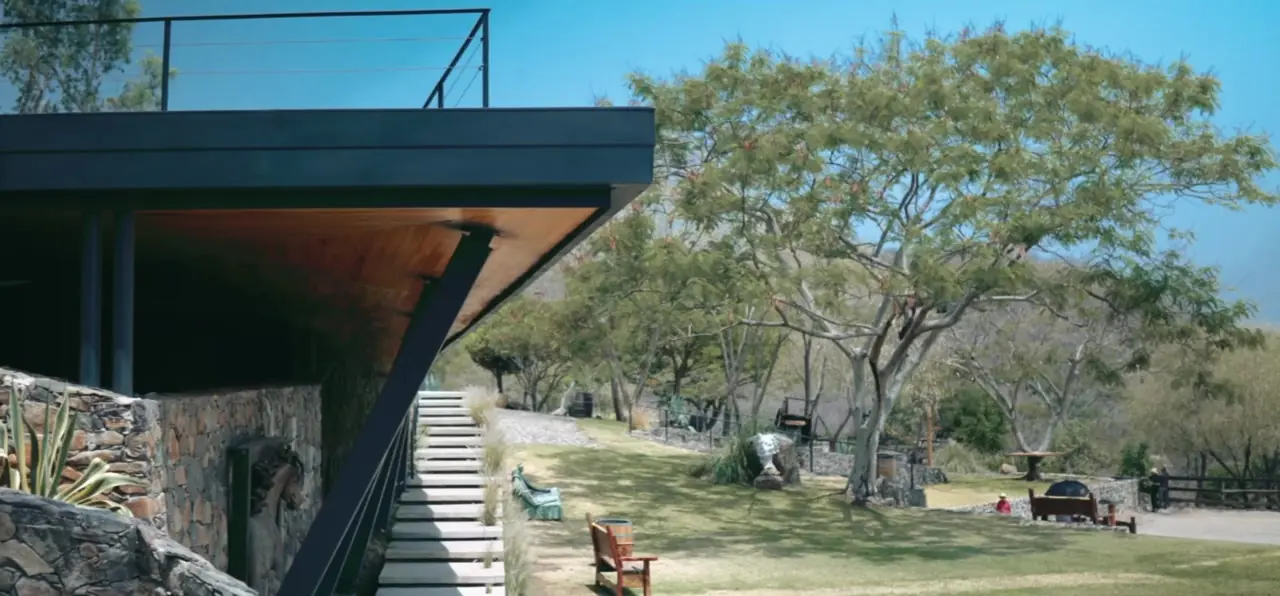 Casa principal del rancho entre árboles, con acero y piedra