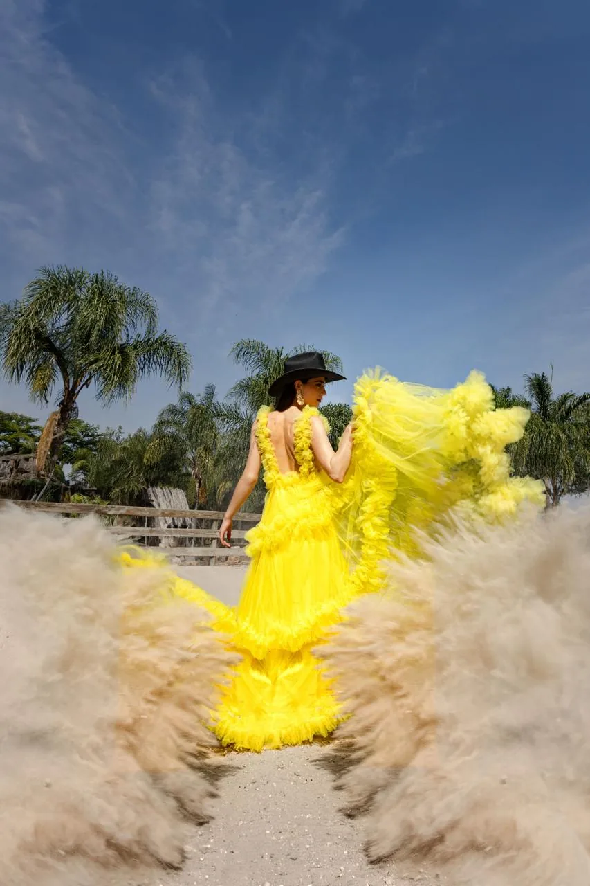 Sesión de moda con vestido amarillo en la pista de arena