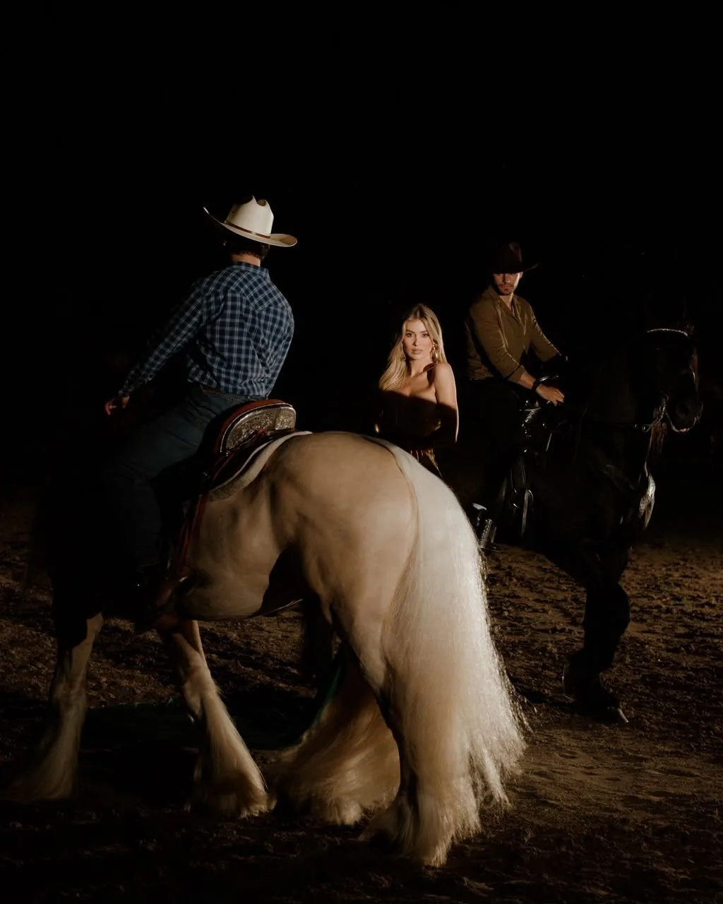 Sesión nocturna en la pista con jinetes, un Gypsy Vanner y un Friesian